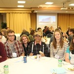 A table of guests smile and enjoy dinner